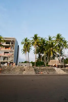 a beach with palm trees and a building at Casa Origen El Zonte in El Zonte