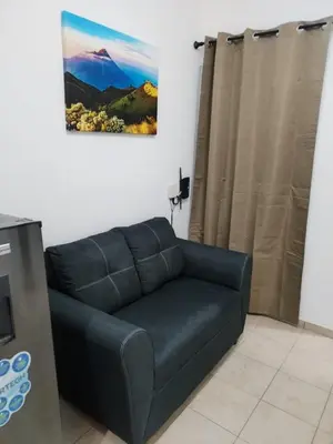 a black couch in a living room with a picture on the wall at House Haciendas del Mediterraneo in Ahuachapán