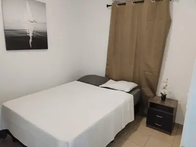 a small bedroom with a bed and a night stand at House Haciendas del Mediterraneo in Ahuachapán