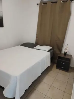 a bedroom with a white bed and a night stand at House Haciendas del Mediterraneo in Ahuachapán