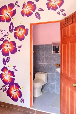a bathroom with a toilet with flowers on the wall at The Salty Dogs in Playa San Blas