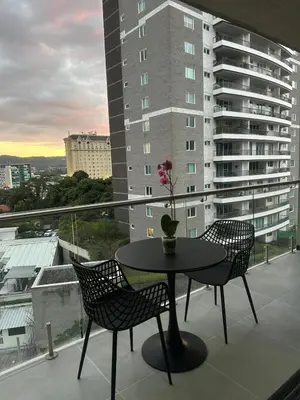 a table and chairs on a balcony with a building at Beko San Benito in San Salvador