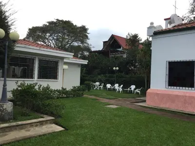 a yard with white chairs and a house at San Antonio Hotel Boutique in Los Naranjos