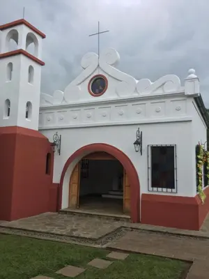 a white and red church with a cross on top at San Antonio Hotel Boutique in Los Naranjos