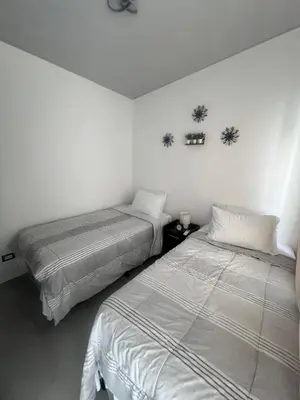 two beds in a room with white walls at Home Sweet Home in San Miguel
