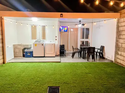 a patio with a table and chairs and a green lawn at Home Sweet Home in San Miguel