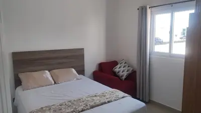 a bedroom with a bed and a red chair at A nice place to enjoy as a family in Metapán