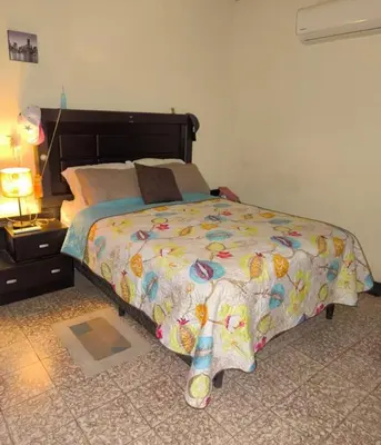 a bedroom with a bed with a comforter on it at La Joyona, Cozy House, Atiquizaya