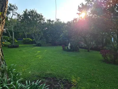a yard with a green lawn with the sun shining at Tata Lodge, Los Romero