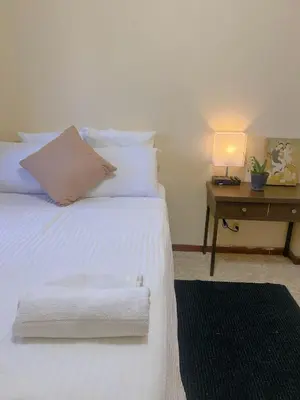 a bedroom with a white bed and a desk with a lamp at Uong Oasis in San Salvador