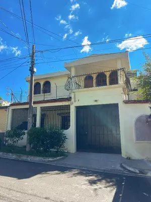 a white house with two garage doors on a street at Uong Oasis in San Salvador