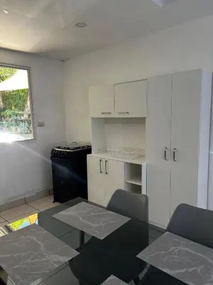 a kitchen with a table and a stove and white cabinets at Hospedaje en san salvador in San Salvador