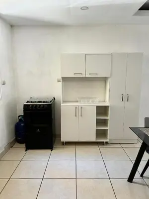 a kitchen with white cabinets and a black stove at Hospedaje en san salvador in San Salvador