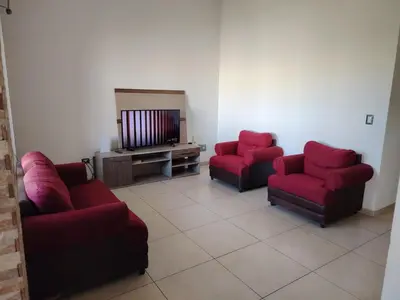 a living room with three red chairs and a television at Family house for 10 guest in Nejapa