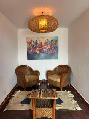 a living room with a table and chairs and a painting at Hotel y Restaurante Buganvilias