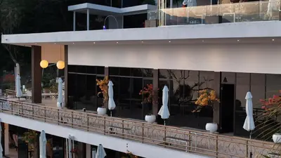 a balcony with white umbrellas and flowers on a building at Hotel y Restaurante Buganvilias