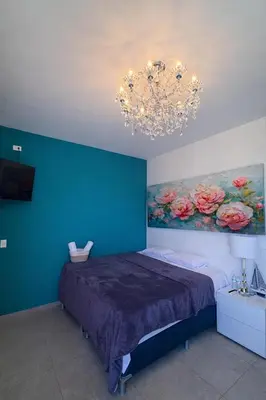 a bedroom with a bed with a blue wall and a chandelier at Hotel y Restaurante Buganvilias
