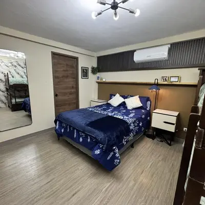 a bedroom with a bed with a blue comforter at Casa Bri in Antiguo Cuscatlán