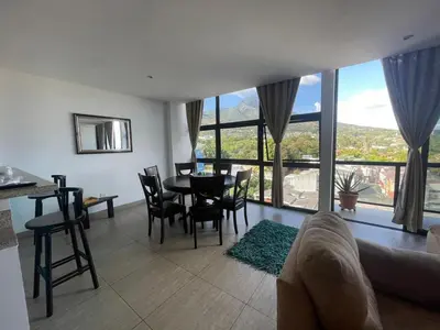 a living room with a table and chairs and a large window at Enjoy San Salvador in Torre 91 in San Salvador