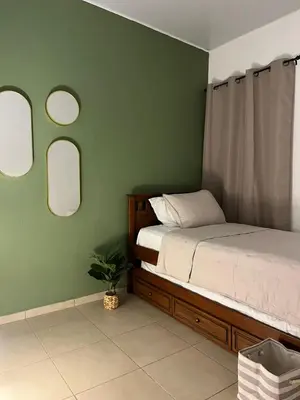 a bedroom with green walls with a bed and mirrors at Aluna House - Nuevo Sitio del Niño in San Juan Opico