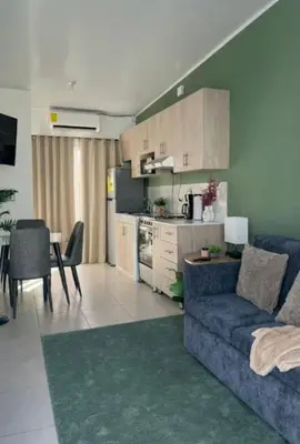 a living room with a blue couch and a kitchen at Aluna House - Nuevo Sitio del Niño in San Juan Opico