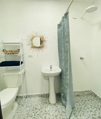 a white bathroom with a toilet and a sink at Hostal la casa de Ross in Santa Ana