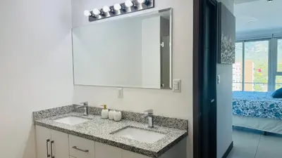 a bathroom with a sink and a mirror and a bed at Torre Puerta el Alma-Luxury Stay-Frente Mall Multiplaza in Ceiba de Guadalupe