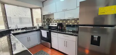a kitchen with white cabinets and a stainless steel refrigerator at Townhouse San Benito, La Mascota Terra in San Salvador