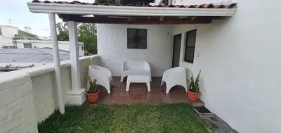 a patio with white chairs on a white house at Townhouse San Benito, La Mascota Terra in San Salvador