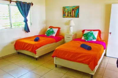 a bedroom with two beds with orange sheets and a window at Casa Libre Guest House in Conchagua