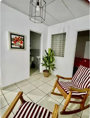 a living room with two chairs and a potted plant at Casa Hogar in Ahuachapán
