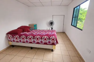 a bedroom with a bed with a red blanket on it at Hostal Casa compartida a 8 mins de San Salvador in San Salvador