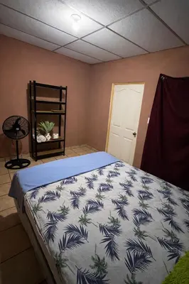 a bedroom with a bed with a blue and white blanket at Hostal Casa compartida a 8 mins de San Salvador in San Salvador