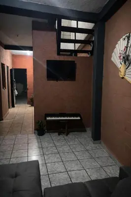 a living room with a piano and a flat screen tv at Hostal Casa compartida a 8 mins de San Salvador in San Salvador