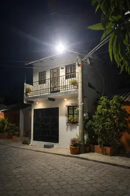 a white house with a balcony and a light on it at Hostal Casa compartida a 8 mins de San Salvador in San Salvador