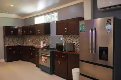 a kitchen with wooden cabinets and a stainless steel refrigerator at Villa Costabay in El Zapote