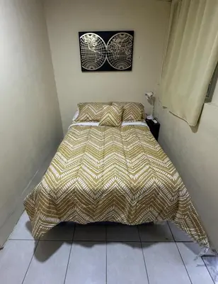 a bed in a bedroom with a comforter on it at Habitacion con aire acondicionado in San Salvador