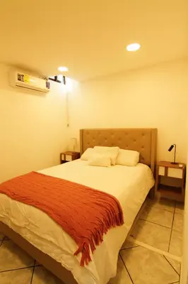 a bedroom with a bed with a red blanket on it at Spacious Home - Cerca de Escalón in San Salvador