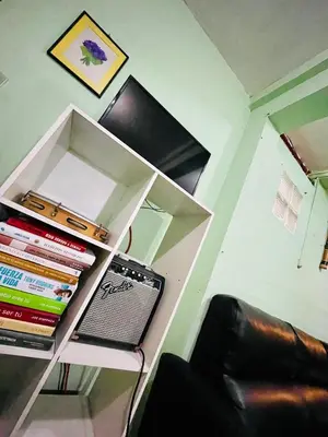 a book shelf with a stack of books next to a chair at Habitación privada en villa familiar en La Libertad in Zaragoza