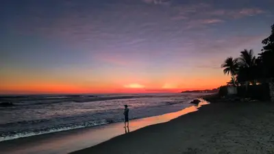 a person standing on the beach at sunset at Apartment in Playa Las Flores La Libertad in La Libertad