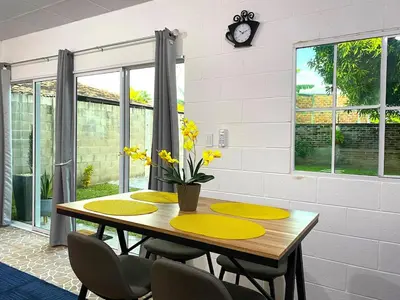 a dining room table with yellow chairs and a clock at Casa Acogedora