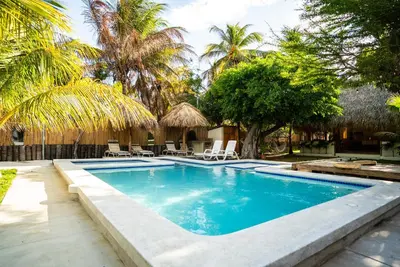 a swimming pool with chairs and palm trees at Villa Con Piscina, Playa, Jacuzzi, Kayaks in Conchagua