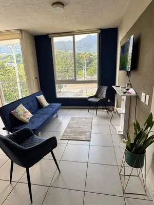 a living room with a blue couch and two chairs at Apartment in Colonia Escalón with pool and gym in San Salvador