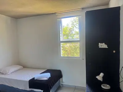 a small bedroom with a bed and a window at Apartment in Colonia Escalón with pool and gym in San Salvador
