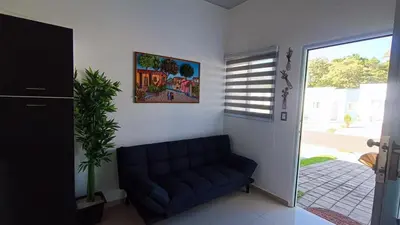 a living room with a blue couch and a window at The small house in Ahuachapán