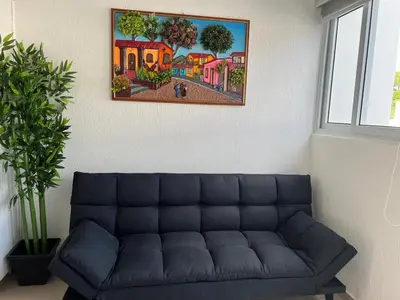 a couch in a living room with a painting on the wall at The small house in Ahuachapán