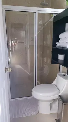 a bathroom with a toilet and a glass shower at The small house in Ahuachapán