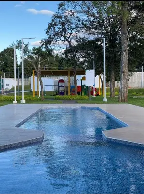 a swimming pool in a park with a playground at The small house in Ahuachapán