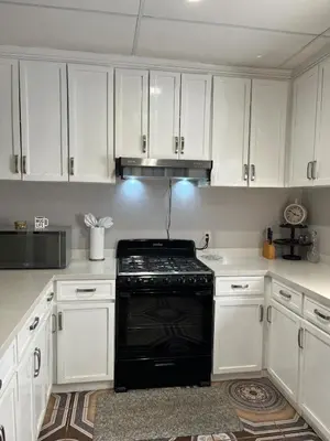 a kitchen with white cabinets and a black stove at Pleasant Vacation Home in Suchitoto