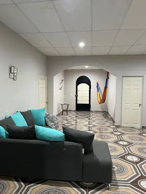 a living room with a black couch and a hallway at Pleasant Vacation Home in Suchitoto